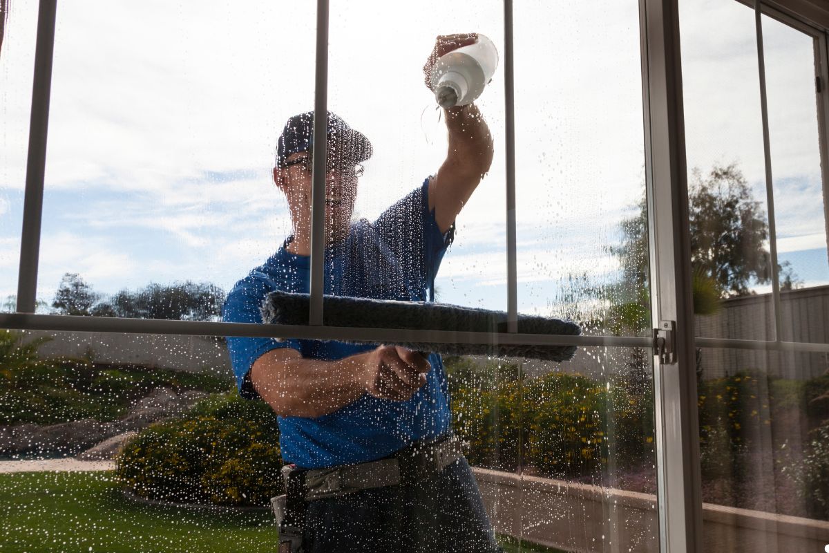 A man using a squeegee to clean a large window, focused on removing streaks for a clear view.